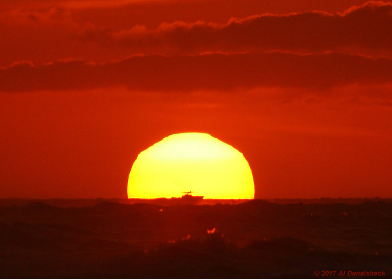 boat silhouetted against sun